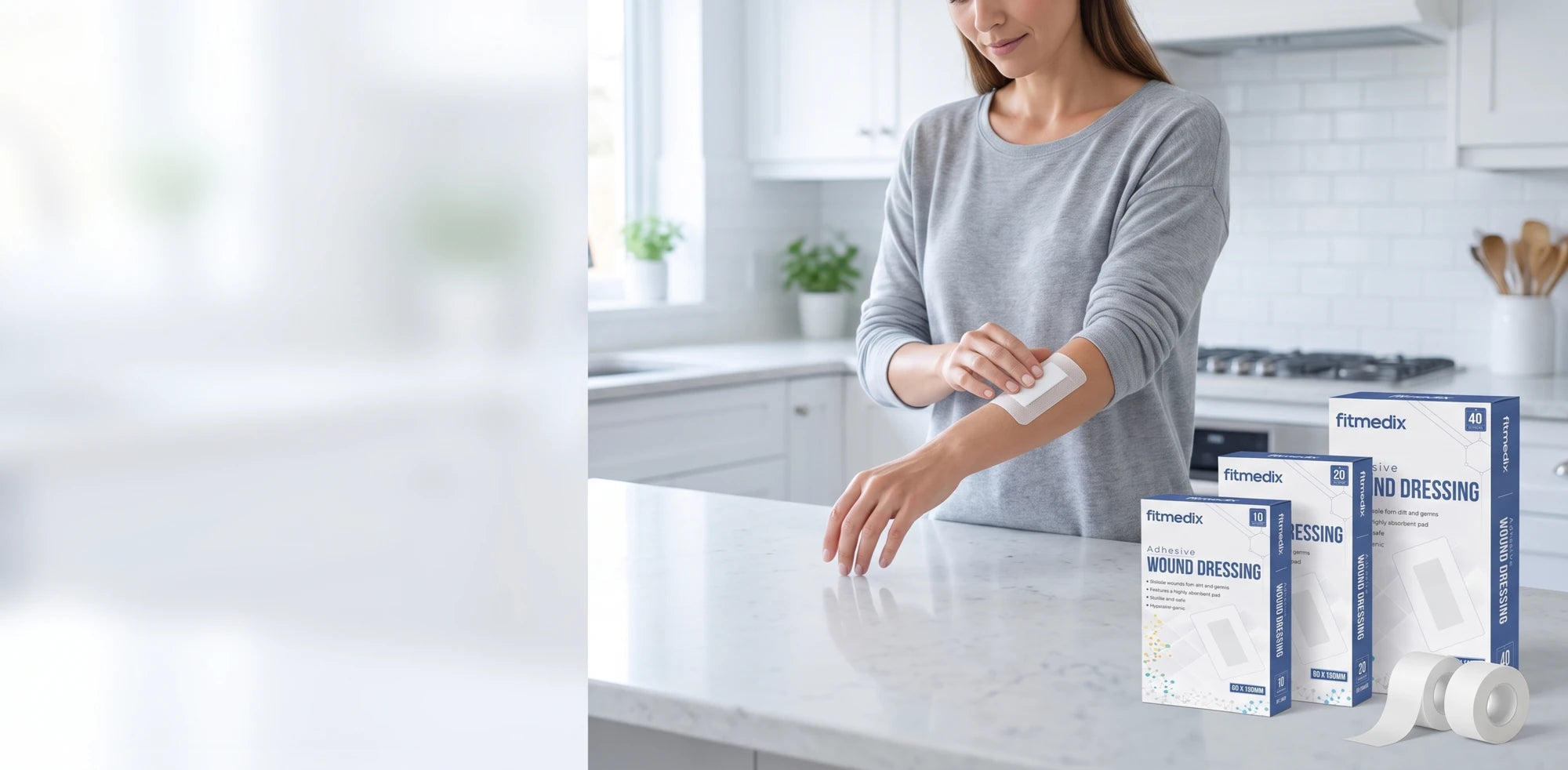 A FitMedix adhesive wound dressing being applied at a kitchen counter, with three pack sizes and tape alongside